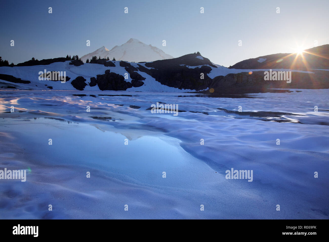 La piscina di acqua di fusione su iced over 14-lago di capra al tramonto, il Monte Baker in background, Ptarmigan Ridge, il Monte Baker National Recreation Area, Washington C Foto Stock
