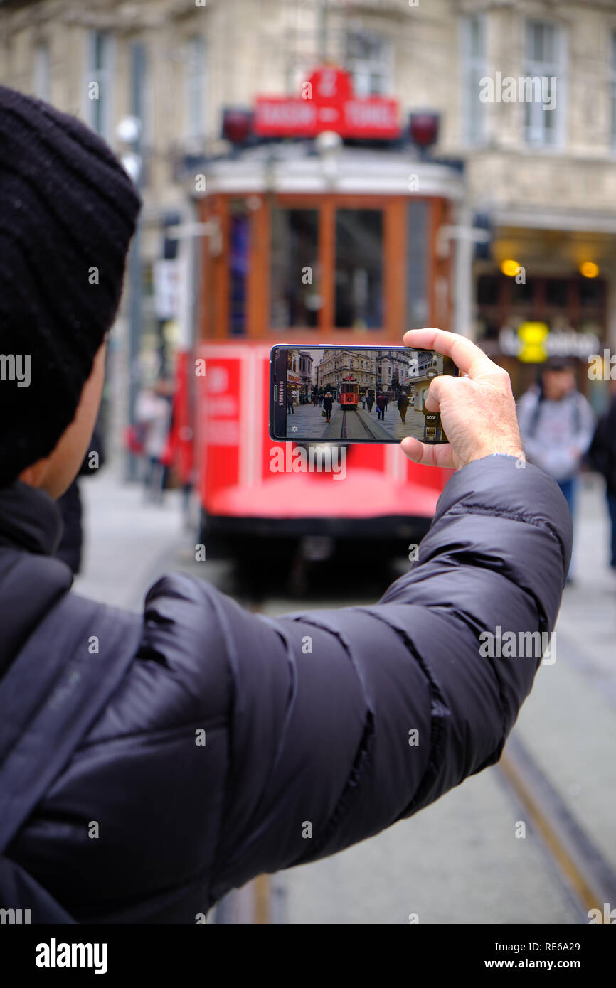 Istanbul - Dicembre 2018 : turistica prendendo foto del Taksim tram storico attraverso strade di Istanbul. Focus su immagine sullo schermo dello smartphone Foto Stock