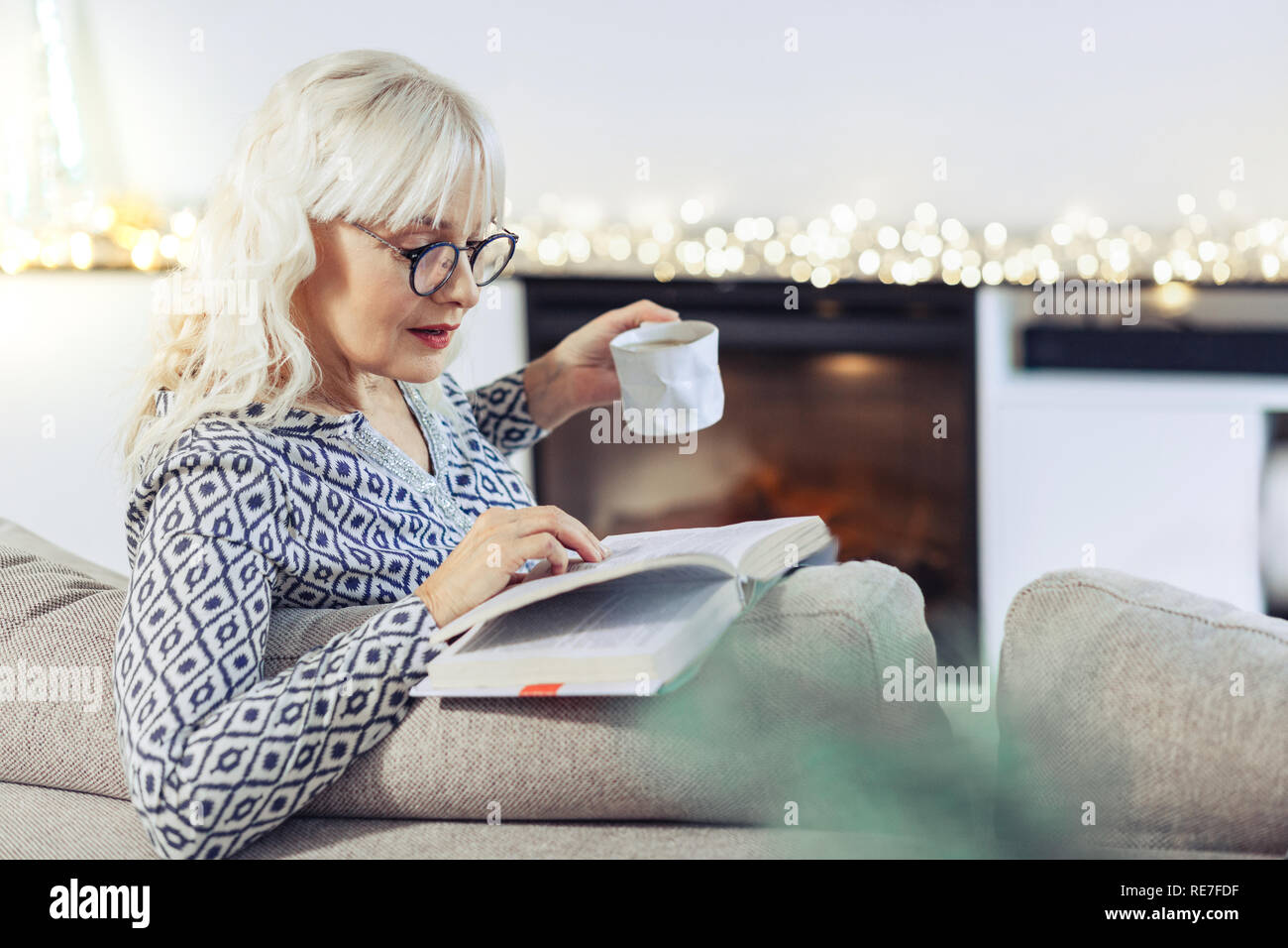 Bella donna positiva la lettura di un libro a casa Foto Stock