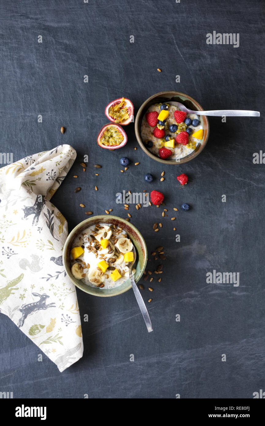 Una sana prima colazione. Porridge con banana, mirtilli, lamponi, frutto della passione, mango e semi. Foto Stock