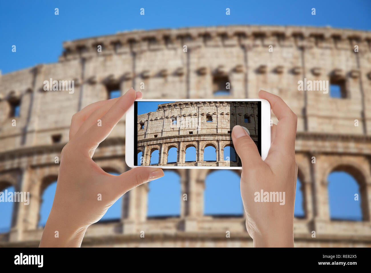 Un uomo è fare una foto del Colosseo contro un cielo blu roma, Italia su un telefono cellulare Foto Stock