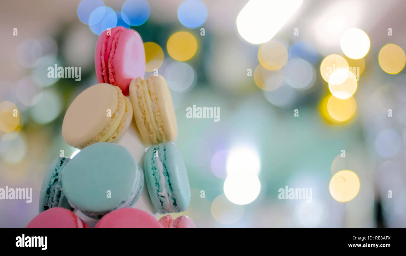 Macaron tower - multicolore di gustosi amaretti francese con Natale bokeh ghirlanda luminosa. Cucina francese, candy, vacanze, anno nuovo e il concetto di cibo Foto Stock