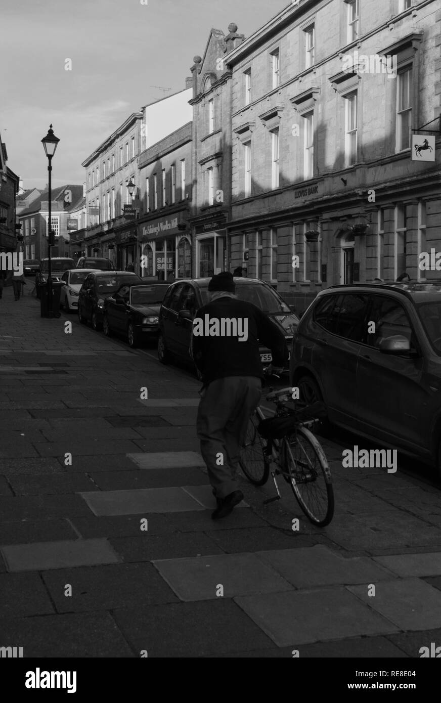 Questa è una foto di un vecchio uomo che cammina la sua bici fino a una strada Foto Stock