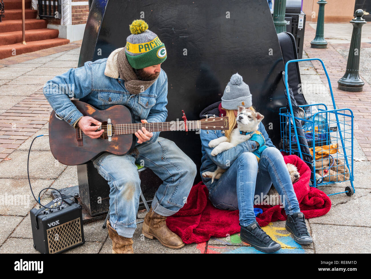 ASHEVILLE, NC, Stati Uniti d'America-1/18/19: un modo di suonare la chitarra busker, accompagnato da una ragazza e due cani. Foto Stock