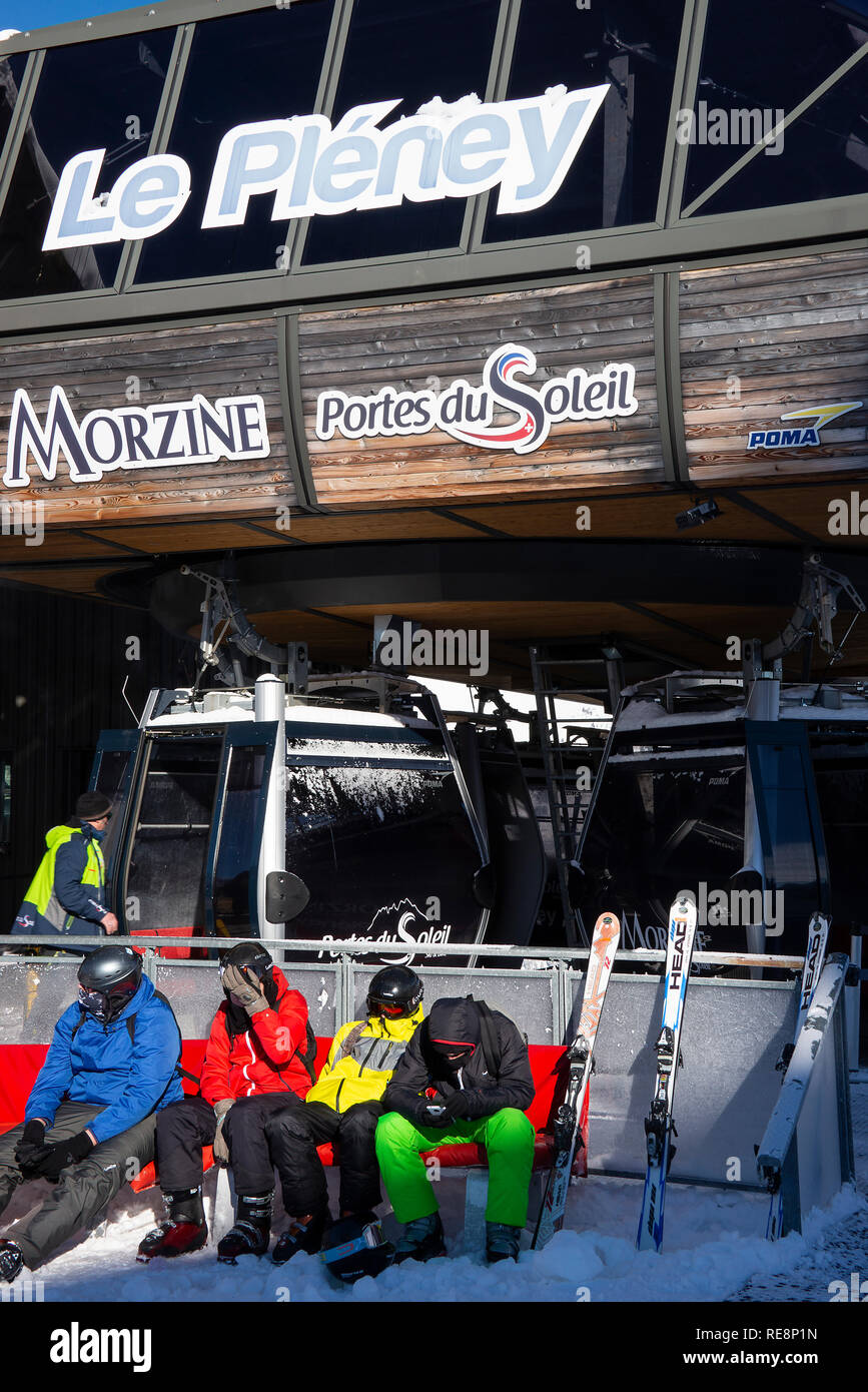 Gli sciatori colorati che indossano un abbigliamento caldo seduta su una panchina di Le Pleney Giro in Gondola a Morzine Haute Savoie Portes du Soleil Francia Foto Stock