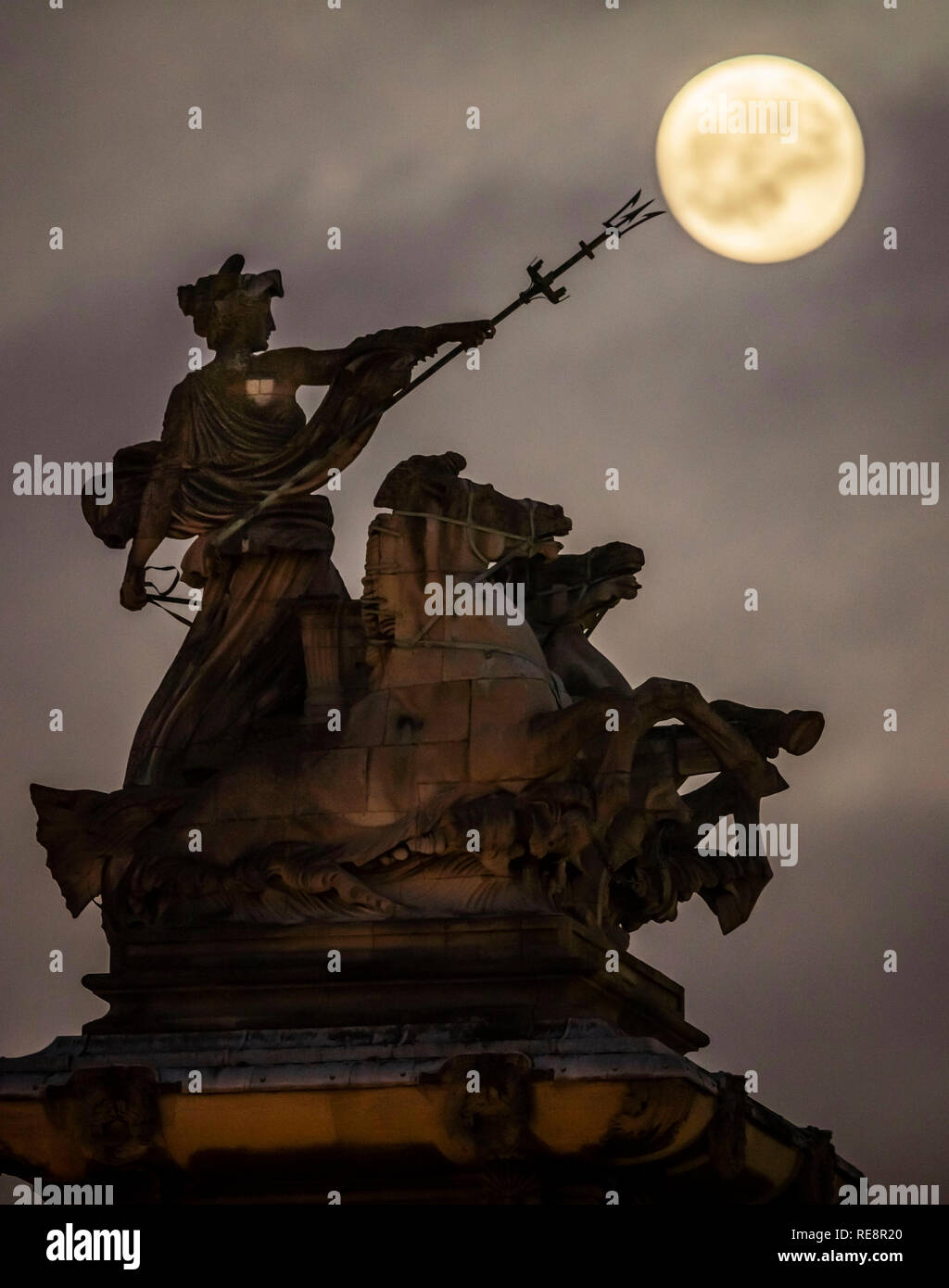 Ritrasmesso per chiarire la terminologia un supermoon sorge sopra la prodezza marittima della statua di Albert Hemstock Hodge ha a Hull Guildhall, precedendo il Lunar Eclipse. Foto Stock