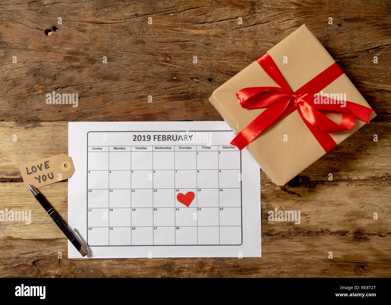 Immagine concettuale del 2019 febbraio calendario e presente dono avvolto con nastro rosso sul rustico tavolo vintage a prepararsi per il giorno di San Valentino Foto Stock