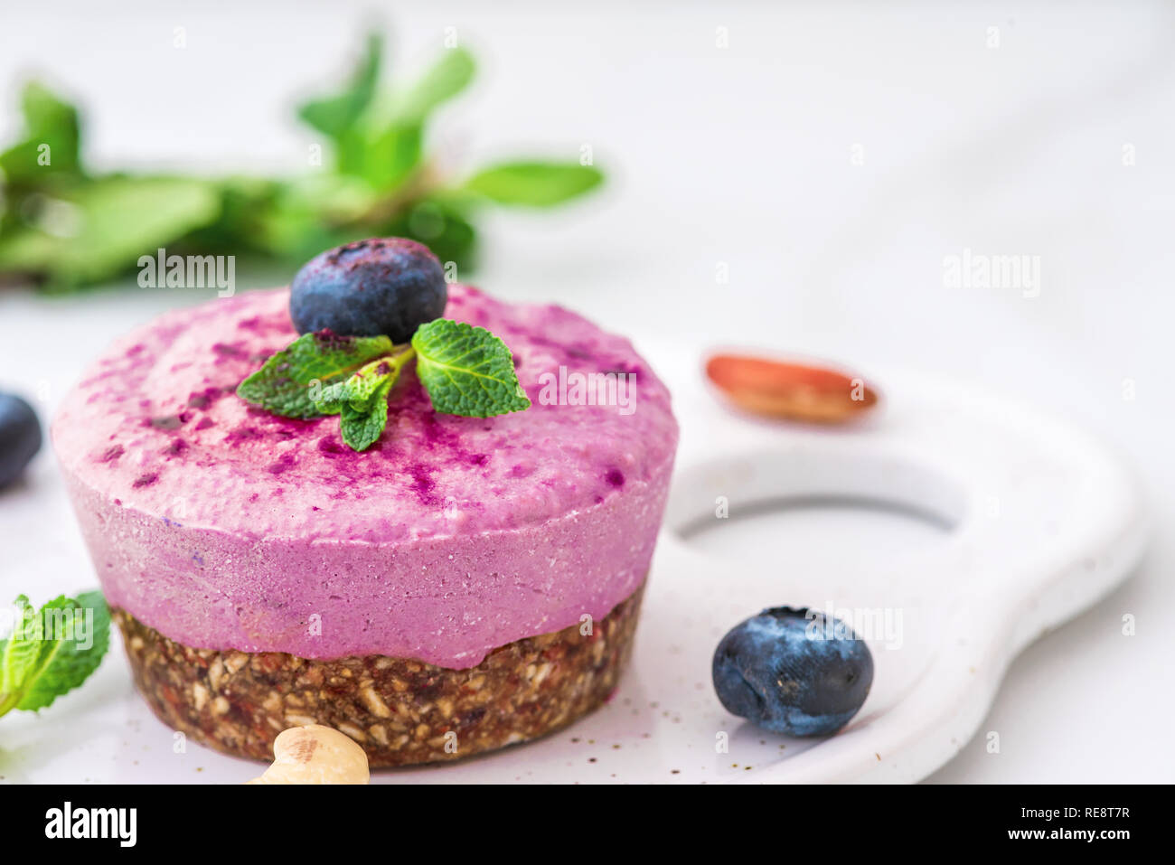 Mirtillo e acai vegane anacardi torta con frutti di bosco freschi, menta, dadi. sano cibo vegan concetto. close up Foto Stock