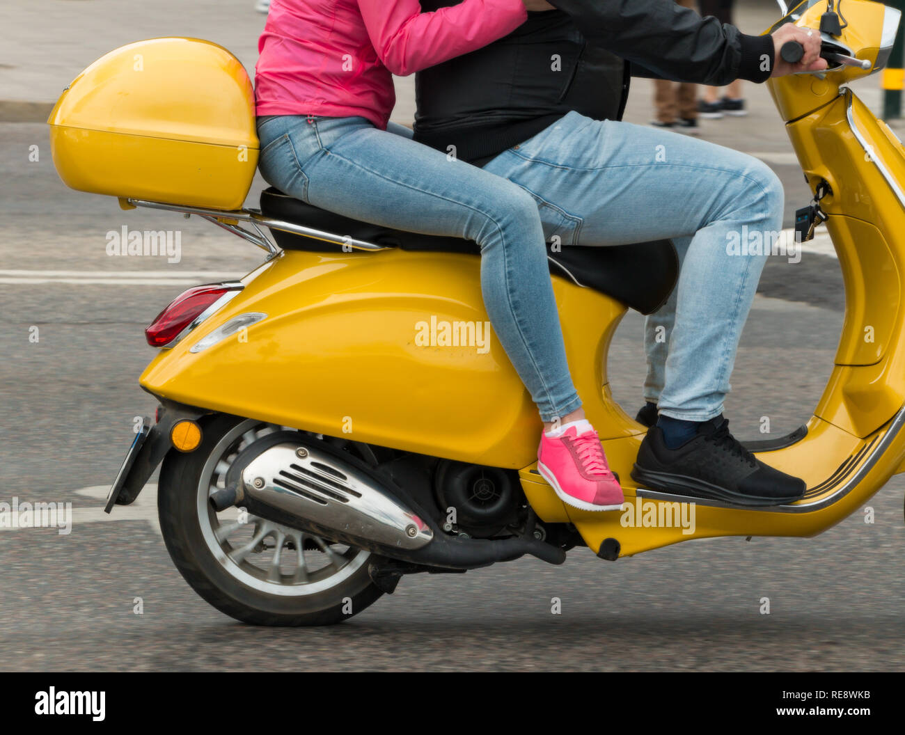 Due persone in sella a un scooter giallo Foto Stock