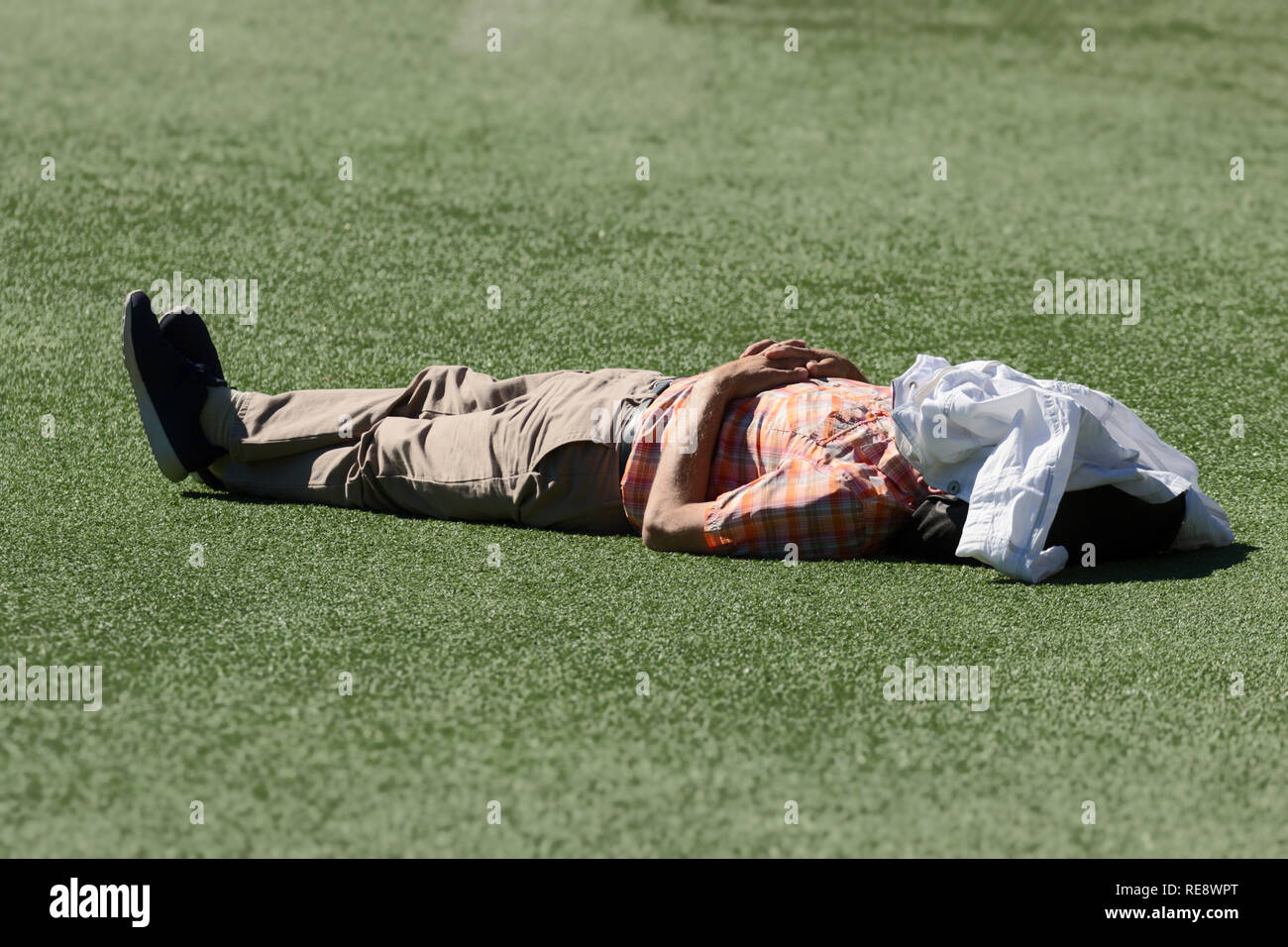 Adulto uomo disteso sull'erba godendo il sole estivo Foto Stock