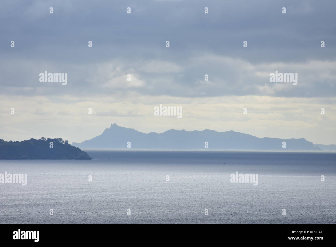 Vista del mare in varie tonalità di grigio e argento con coste distanti sotto il cielo nuvoloso. Foto Stock