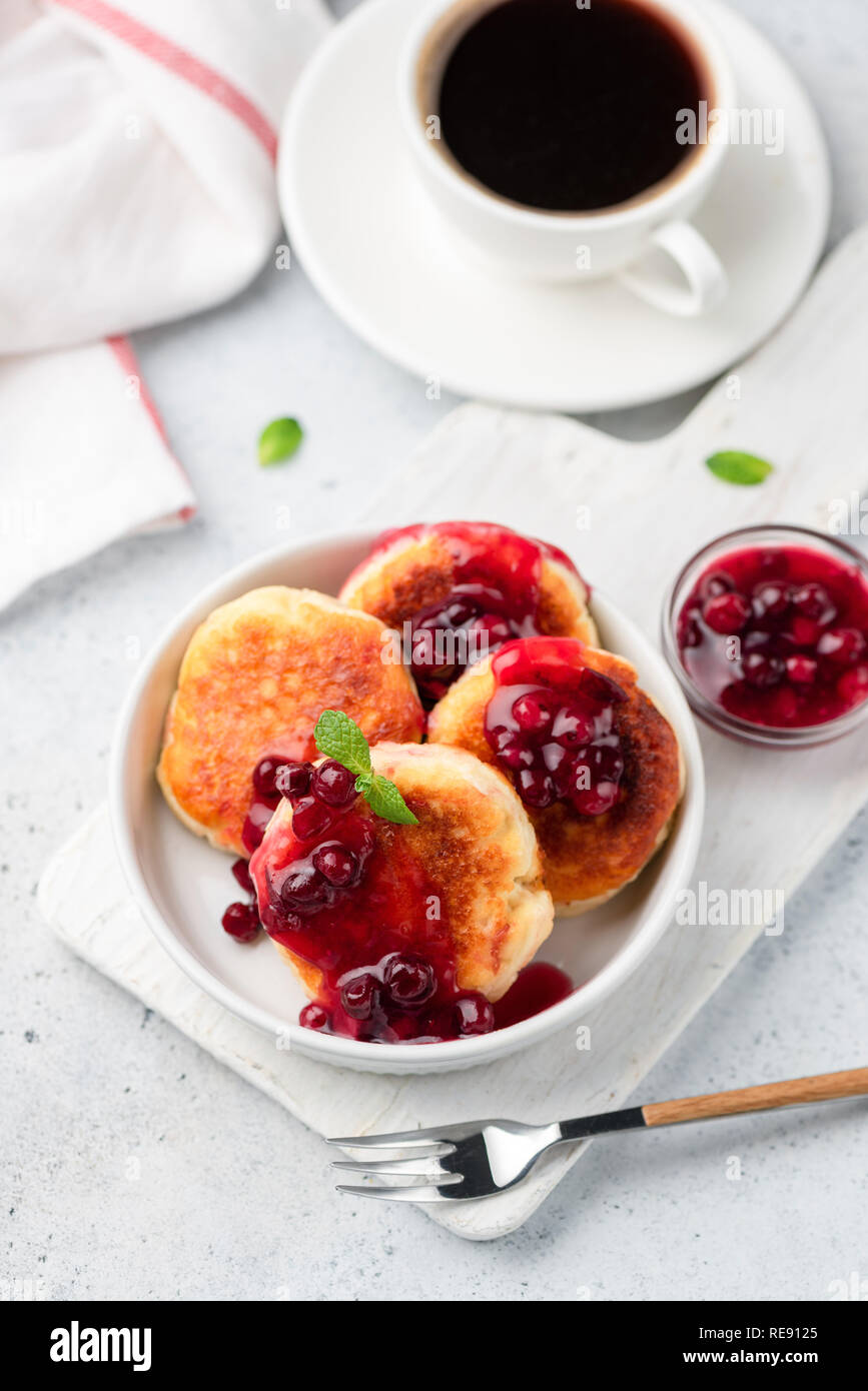 Syrniki cottage, frittelle di formaggio con salsa di frutti di bosco e la tazza di caffè nero. Vista dall'alto, il fuoco selettivo Foto Stock