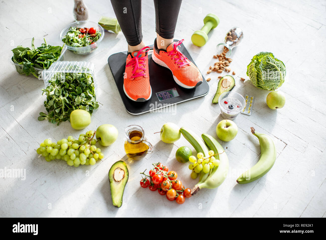 Sport donna di peso sulla bilancia con il cibo sano intorno a. La perdita di peso, cibo sano e sport concetto di stile di vita Foto Stock