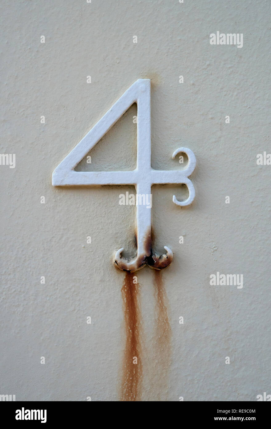 Una chiusura di un metallo numero quattro Numero porta dipinta di bianco e andando Rusty Foto Stock
