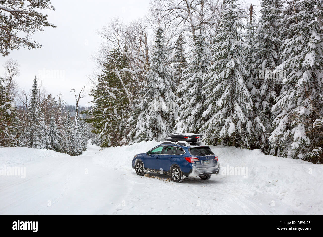 Un blu station wagon auto parcheggiate su una coperta di neve sentiero forestale nei boschi del nord del Minnesota, Stati Uniti Foto Stock