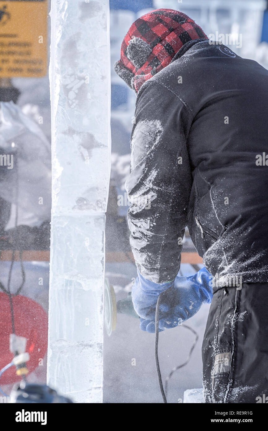 Scultore di ghiaccio utilizzando una smerigliatrice elettrica per lucidare una lastra di ghiaccio presso il Lago Louise Ice Magic Festival nel Parco Nazionale di Banff, Alberta Canada Foto Stock
