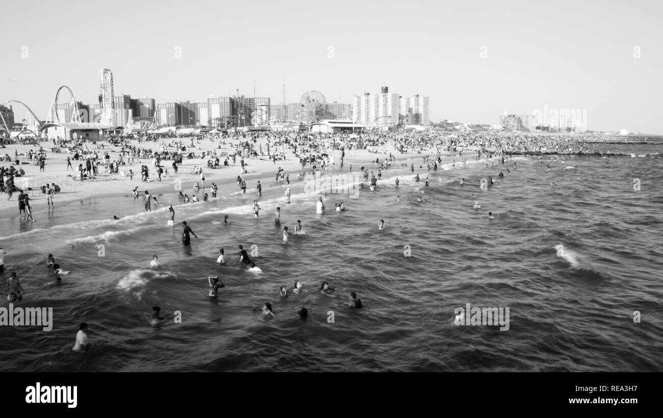 Beachgoers godetevi l'oceano su Coney Island in una calda giornata estiva Foto Stock