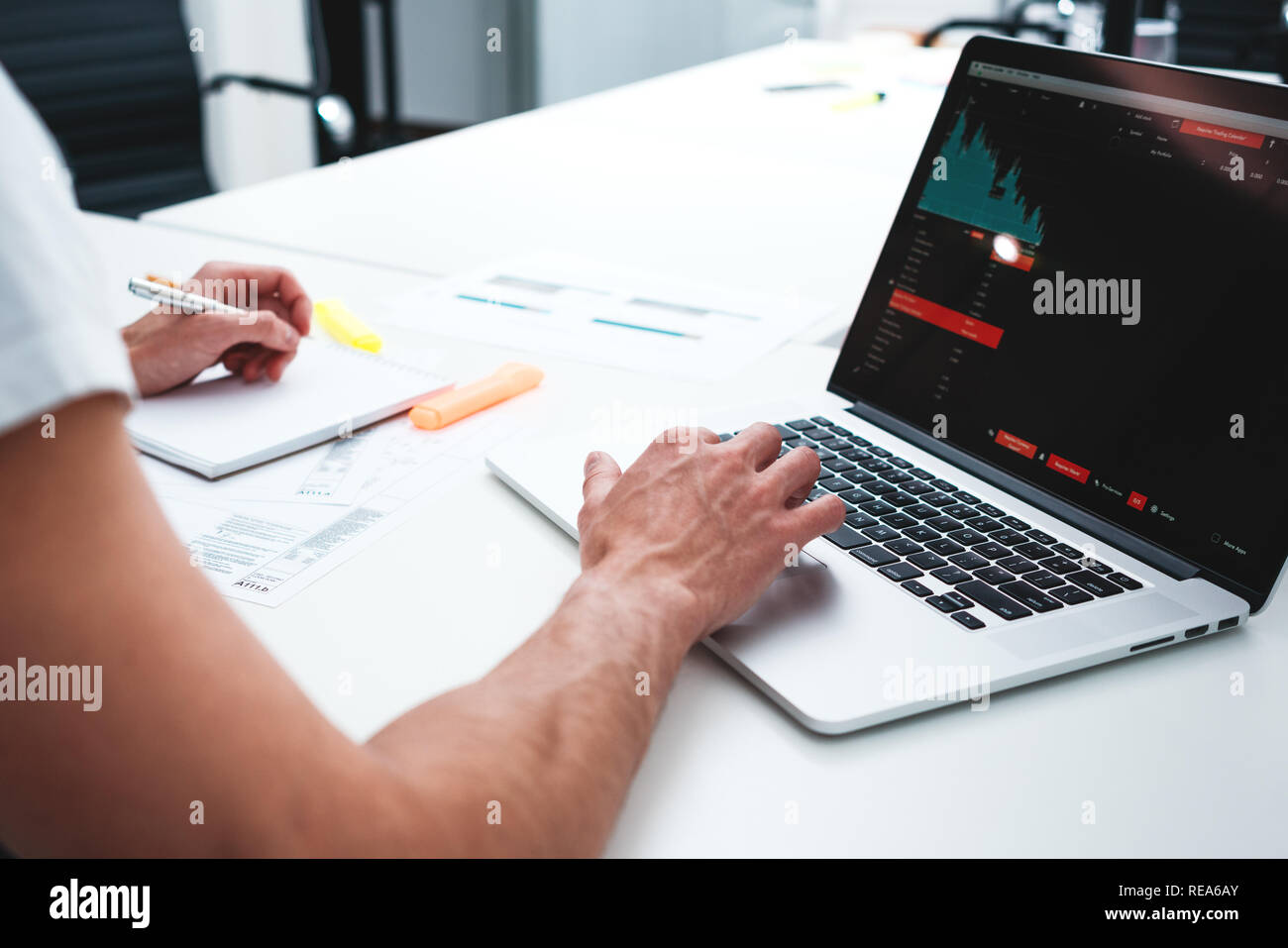 Un collega Uomo con laptop e blueprint di stampati in ufficio moderno. Designer grafico uomo che lavora sul posto di lavoro Foto Stock