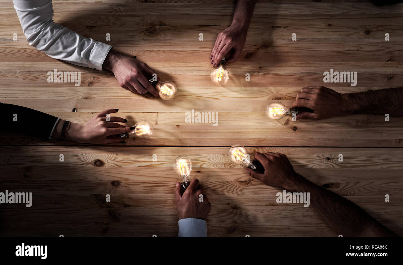 Il lavoro di squadra e il concetto di brainstorming con gli imprenditori che condividono un'idea con una lampada. Concetto di startup Foto Stock