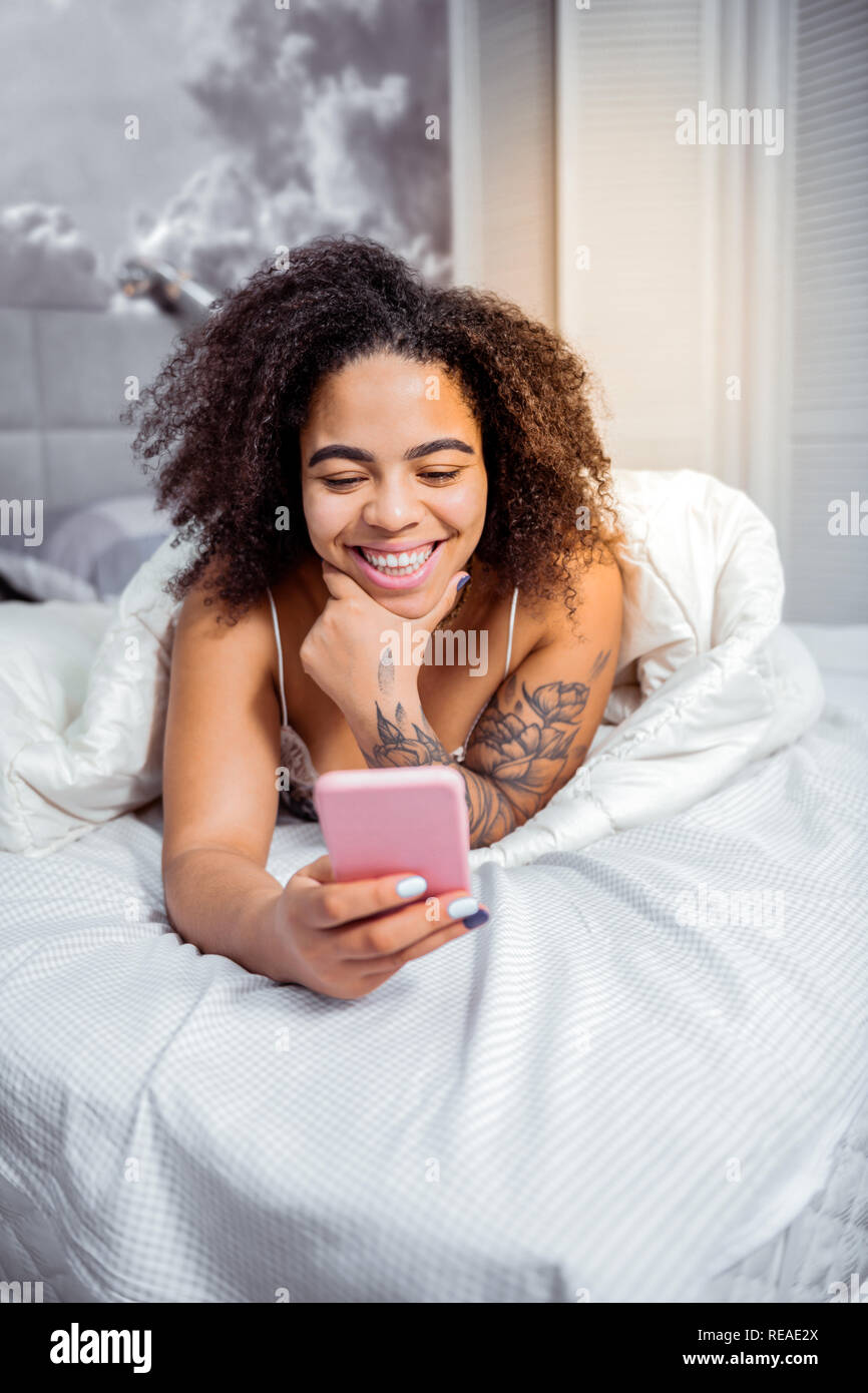 Sorridente donna attraente avente grande mattina mentre giaceva a letto Foto Stock