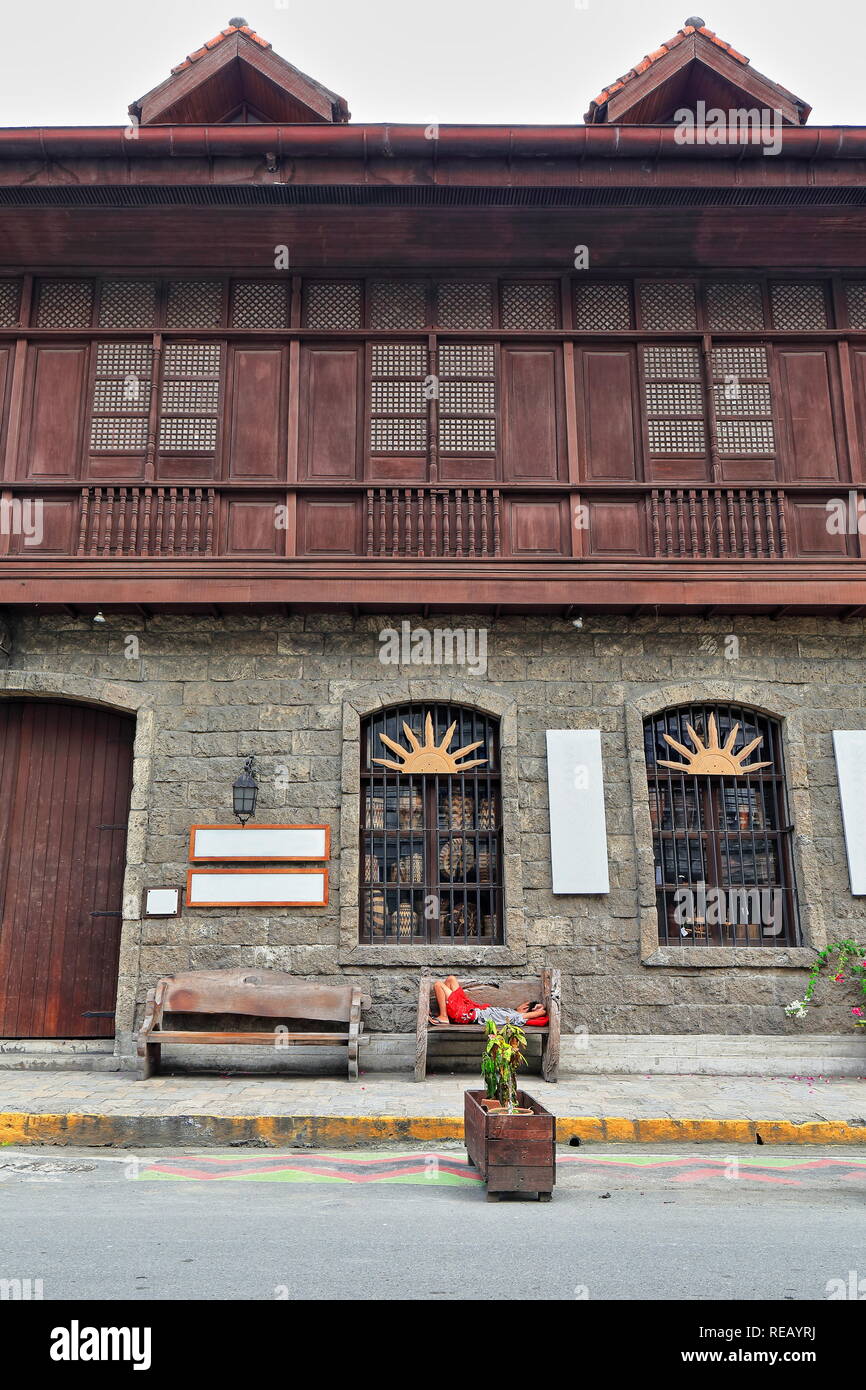 Guy dormire su un banco di lavoro-El Amanecer edificio sulla Luna Generale San-muro di pietra e griglia di ferro finestre al piano terra-fila di tralicciati in legno oriel windows Foto Stock