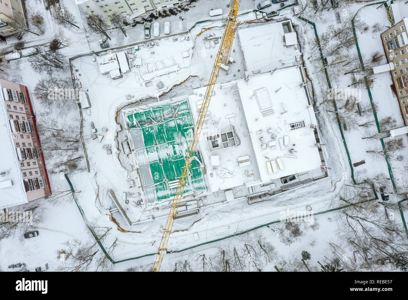 Antenna di immagine superiore di giallo gru a torre lavorando alla costruzione della città sito in inverno Foto Stock