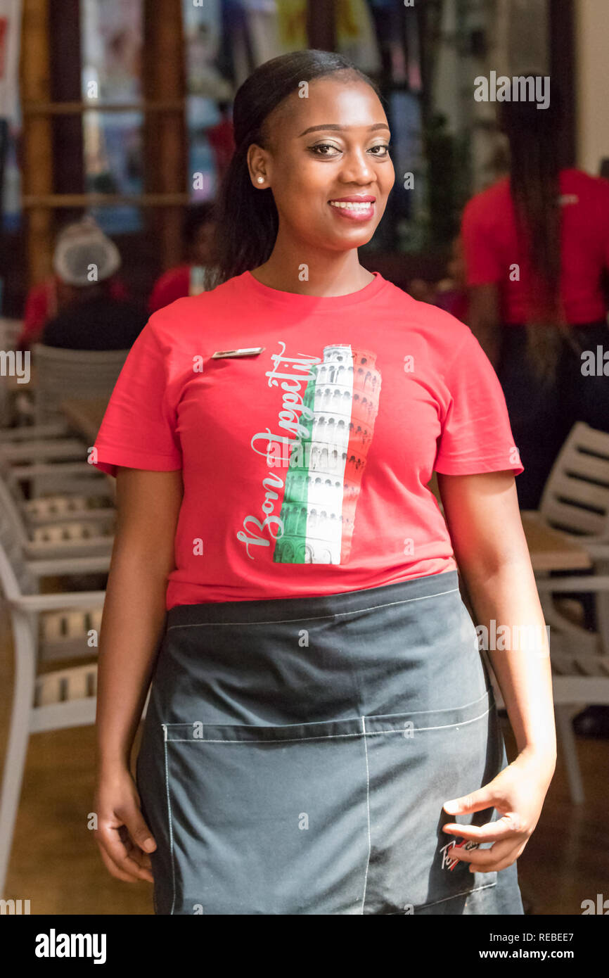 Durban, Sud Africa - Gennaio 06th, 2019: Ritratto di una cameriera nero donna sudafricana con trecce sorridente guardando la fotocamera a Durban Foto Stock Durban, Sud Africa - Gennaio 06th, 2019: Ritratto di una cameriera nero donna sudafricana con trecce sorridente guardando la fotocamera a Durban Foto Stock