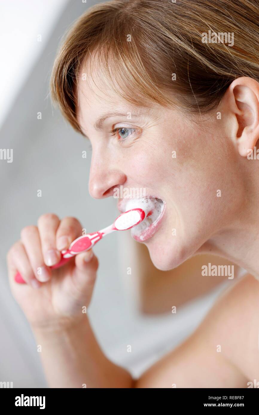 Giovane donna spazzolare i suoi denti in un bagno Foto Stock