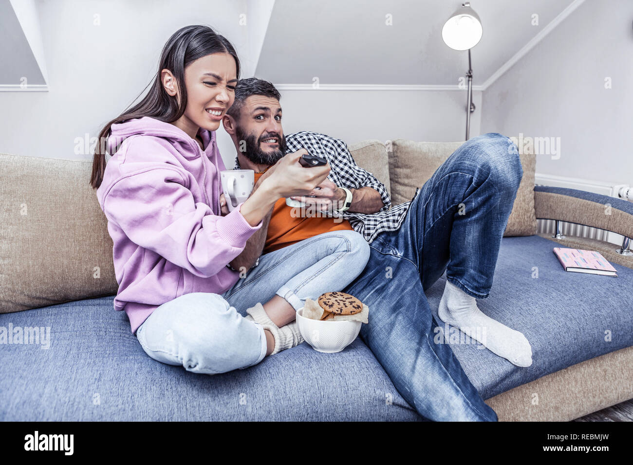 Emotivo bella donna asiatica prendendo un telecomando Foto Stock