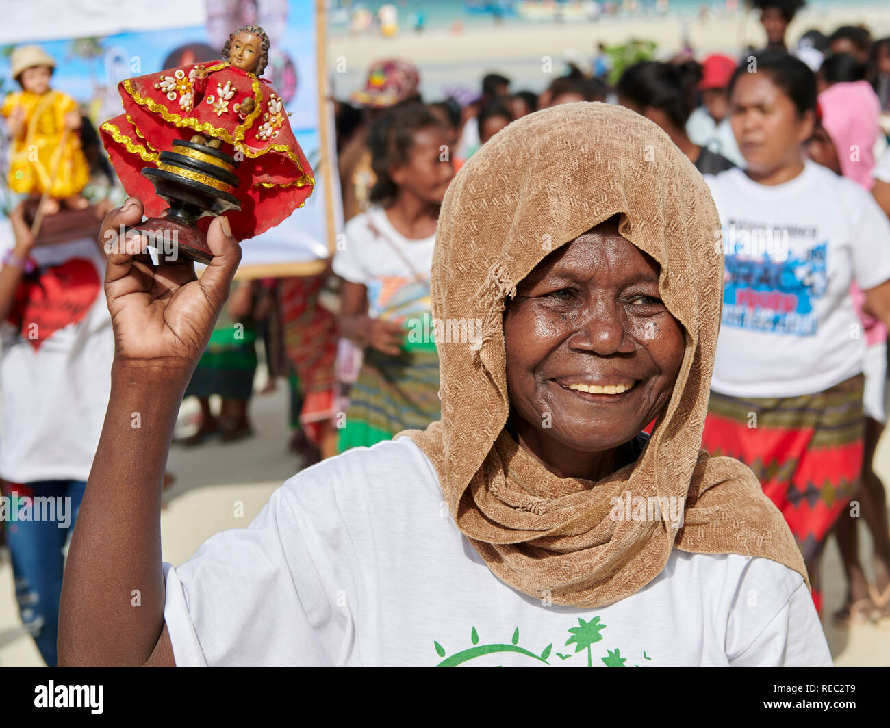 Vecchio elemento femmina degli indigeni Ati comunità è unire la parata Ati-Atihan, tenendo una replica di Santo Nino, lungo la spiaggia di sabbia bianca di Boracay. Foto Stock