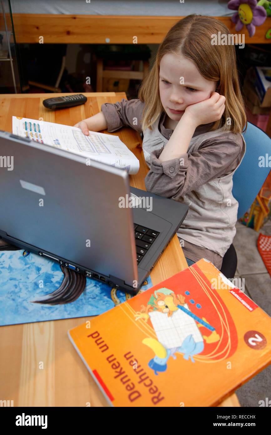 Ragazza 7 anni, lavorando con un computer a casa nella sua stanza, facendo i compiti di scuola, software didattico Foto Stock
