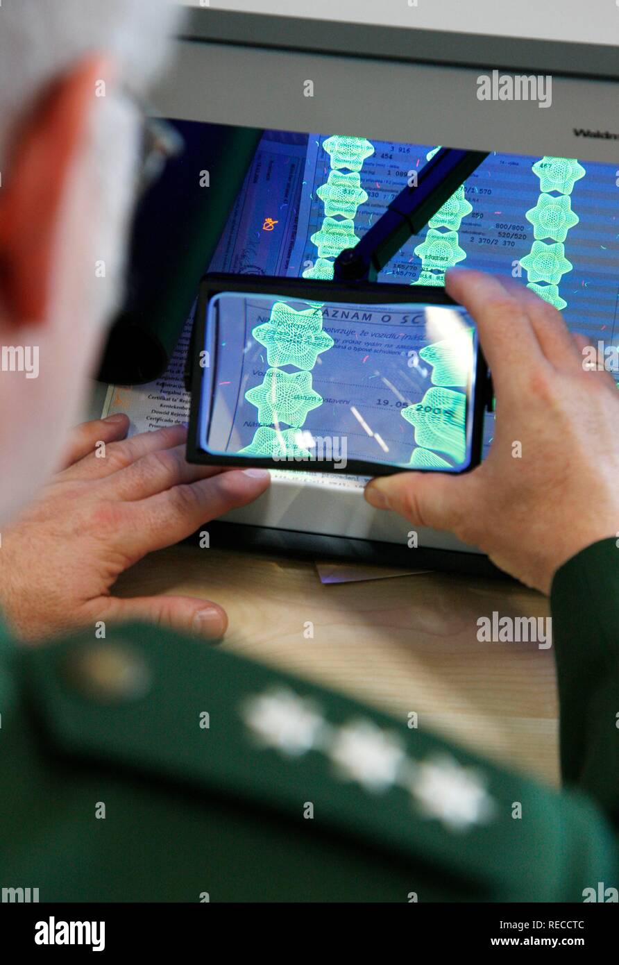 Ispezione di polizia, la convalida di documenti, i documenti dell'auto, utilizzando luce UV ed una lente di ingrandimento mobile della stazione di controllo della Foto Stock