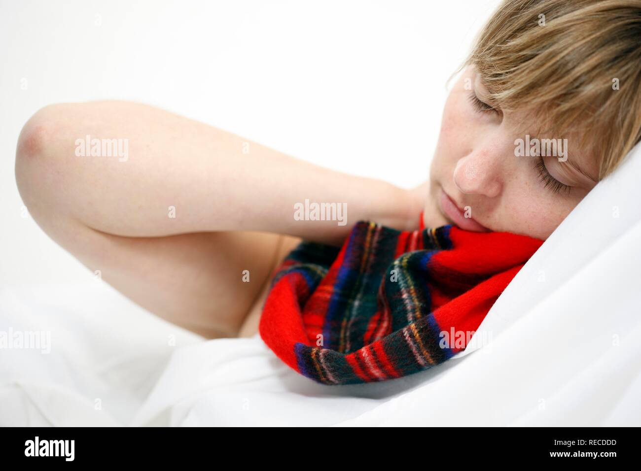 Una giovane donna con un mal di gola e freddo nel letto, con una sciarpa Foto Stock