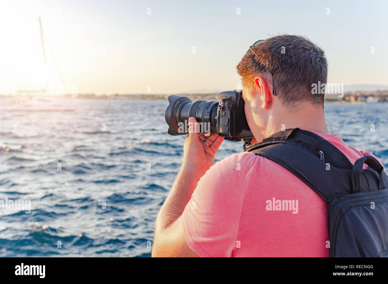 L'uomo con una telecamera a fotografare il tramonto sul mare. Foto Stock