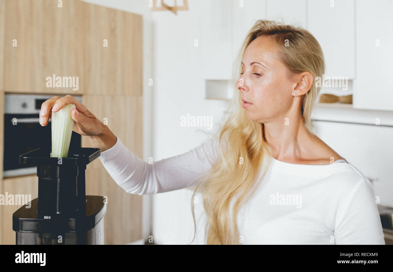 Uno stile di vita sano concetto. Donna 30-40 anni la cottura detox cocktail per la prima colazione a casa in cucina Foto Stock
