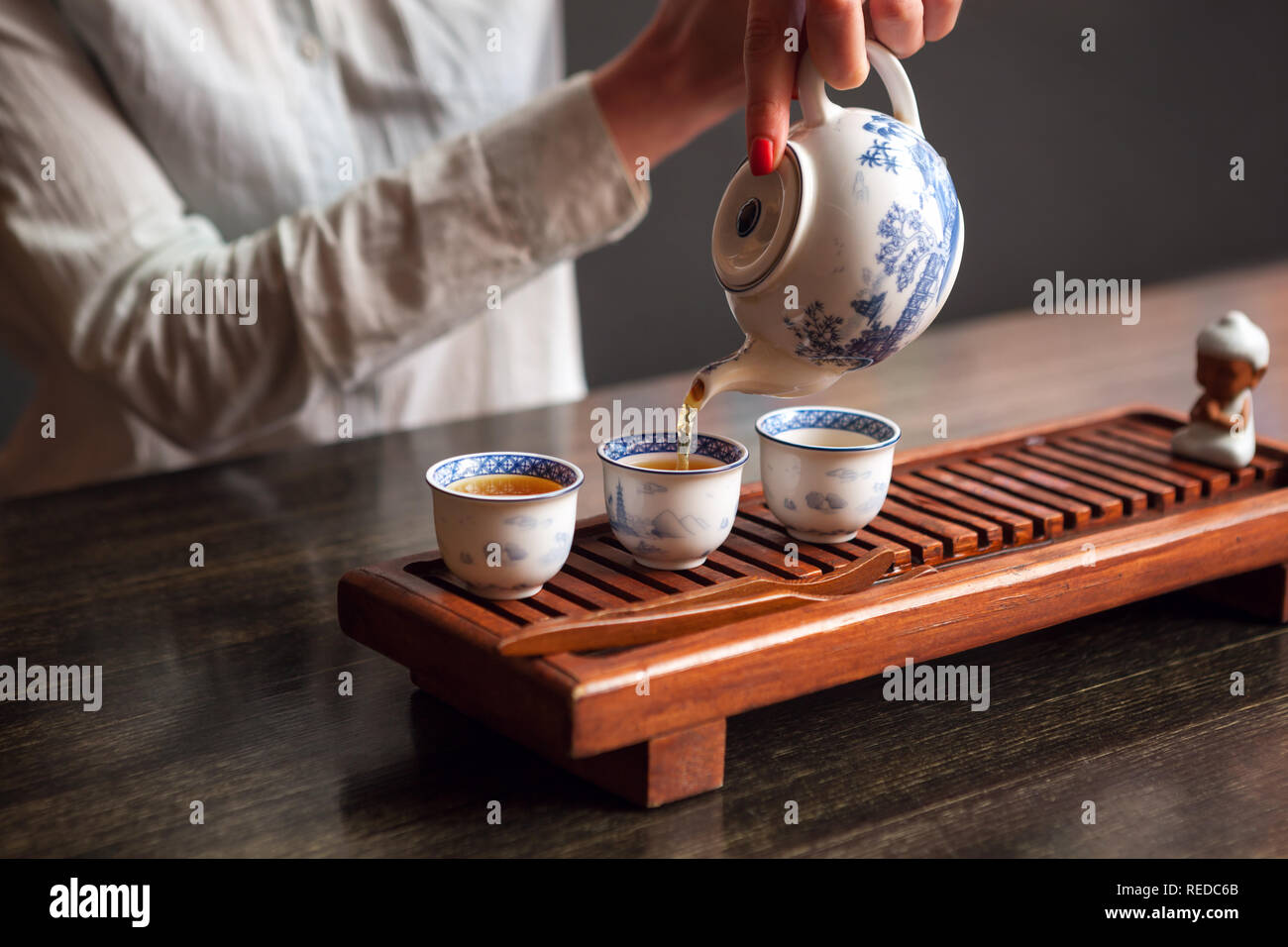 Ritagliato colpo di donna versando il tè in cinese tradizionale teaware. Foto Stock