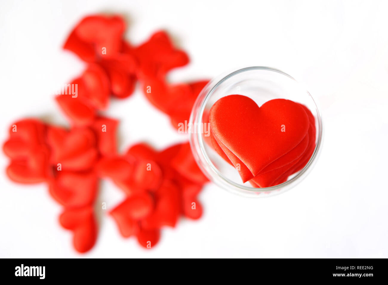 Molti cuori rossi in un vetro trasparente su uno sfondo bianco. Giorno di San Valentino. Congratulazioni per il giorno di San Valentino. Foto Stock
