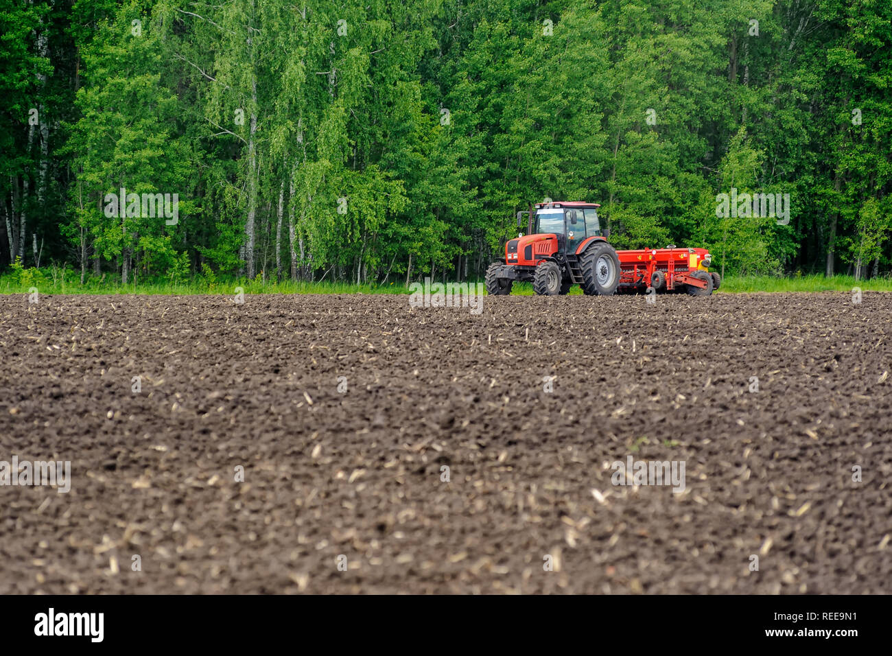 Verhovina, Russia - 30 Giugno 2017: Contadino con il trattore la semina - semina in campi agricoli Foto Stock