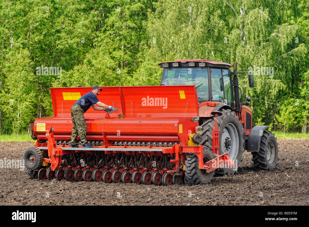 Verhovina, Russia - 30 Giugno 2017: Contadino con il trattore la semina - semina in campi agricoli Foto Stock