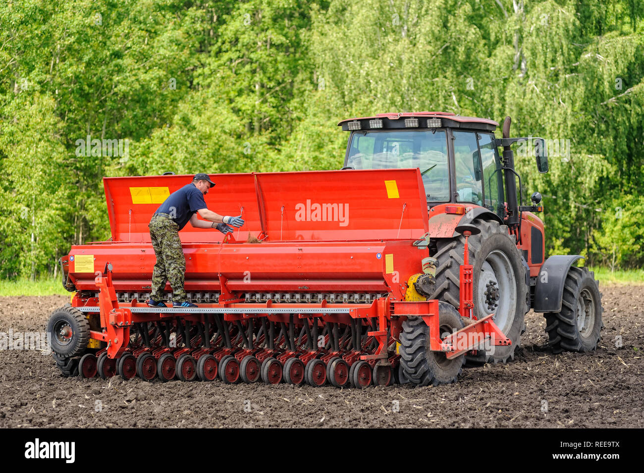 Verhovina, Russia - 30 Giugno 2017: Contadino con il trattore la semina - semina in campi agricoli Foto Stock