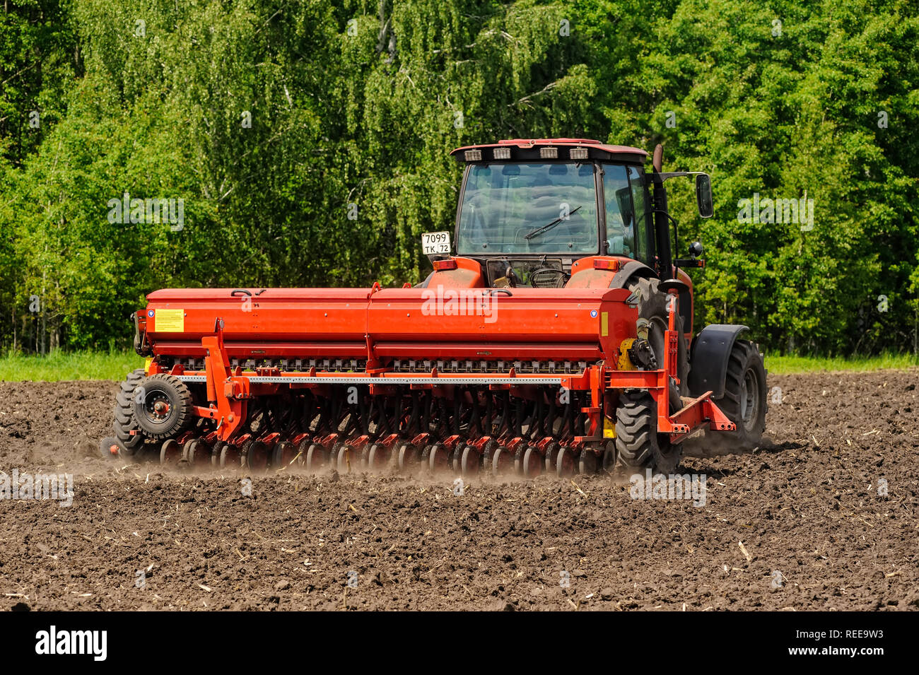 Verhovina, Russia - 30 Giugno 2017: Contadino con il trattore la semina - semina in campi agricoli Foto Stock