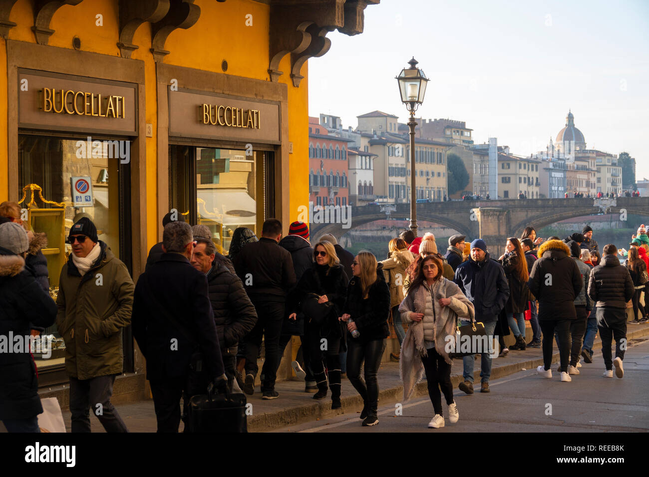 Italia Firenze Firenze un sacco di turisti a piedi lungo il fiume Arno vicino a Ponte Vecchio e la Buccellati gioielleria in inverno Foto Stock