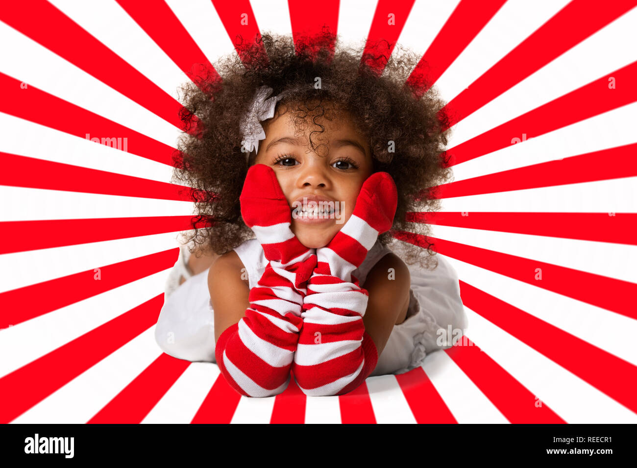 Ritratto di una scuola materna allegro bambino ragazza che stabilisce. Studio shot. Rosso e bianco sfondo geometrica Foto Stock