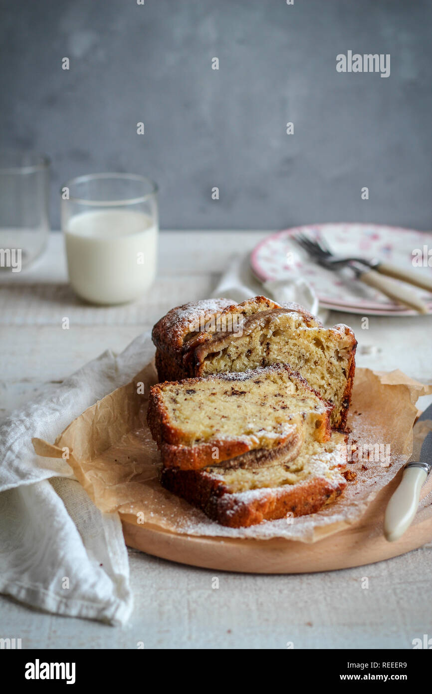 Fette di torta su un vassoio di legno e un bicchiere di latte su sfondo scuro Foto Stock