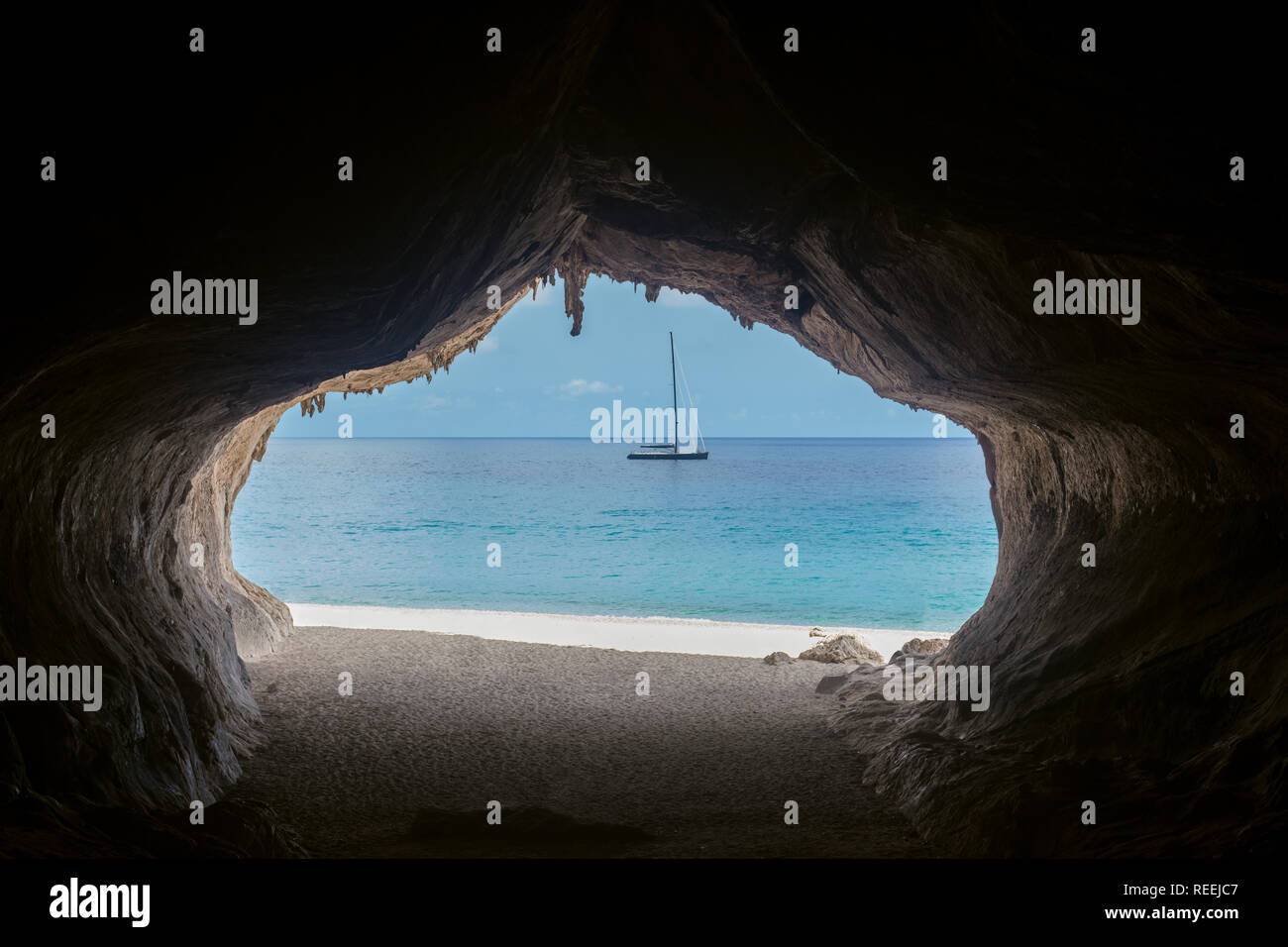 Uscire dalla grotta si affaccia su uno splendido mare e barca a Cala Luna Beach, l'isola di Sardegna, Italia Foto Stock