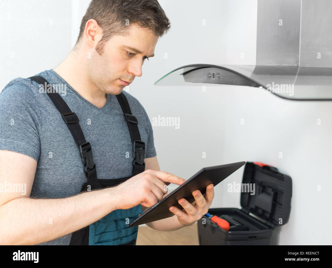 Tuttofare facendo ispezione della cappa aspirante in cucina. Foto Stock