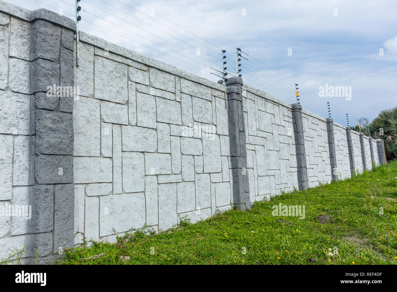 Confine di otto piedi parete struttura di recinzione grigio cemento design arredamento con scosse elettriche fili. Foto Stock