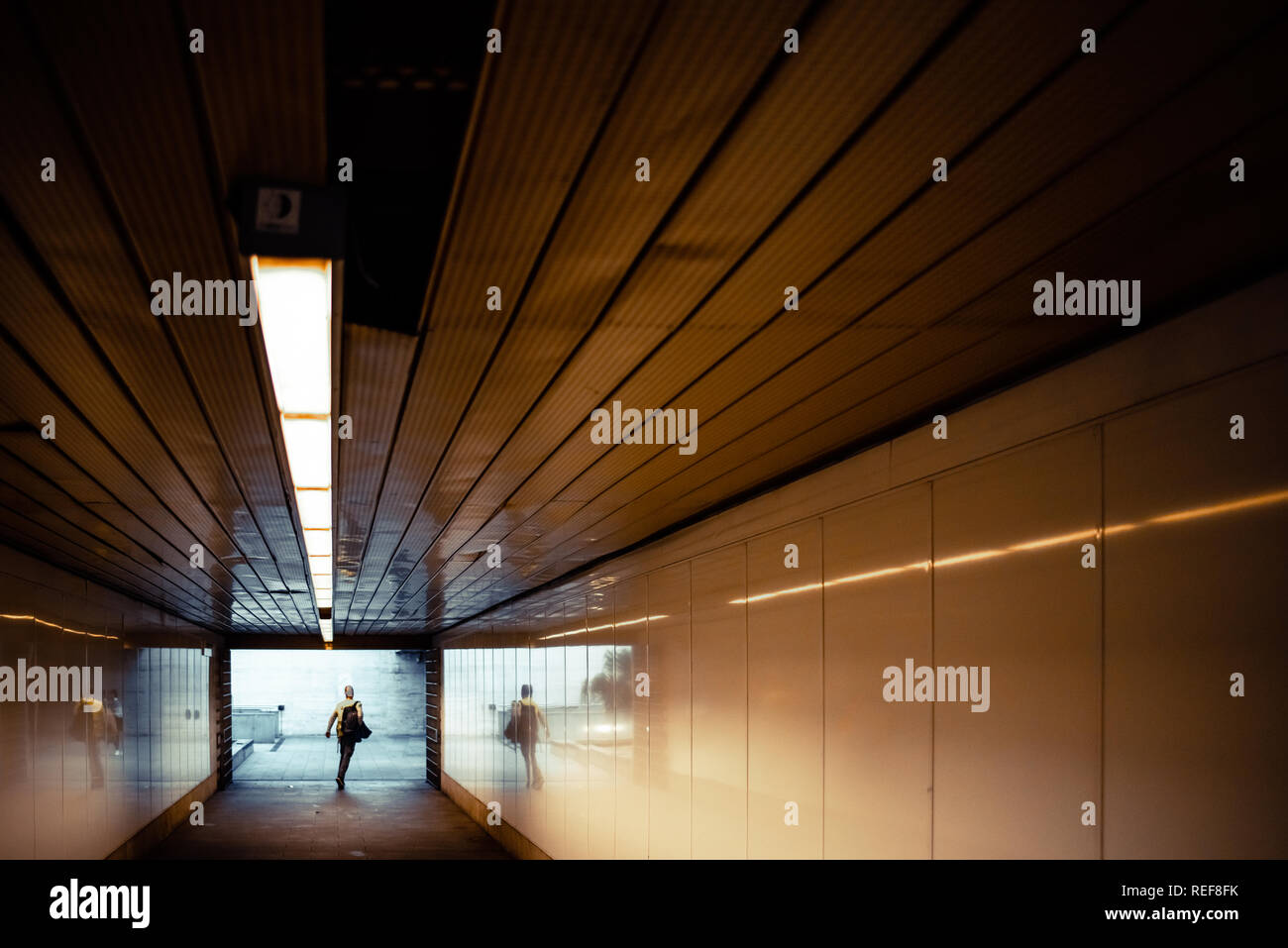 Passeggeri in fretta alla fine di un tunnel all'ingresso della stazione della metropolitana. Foto Stock