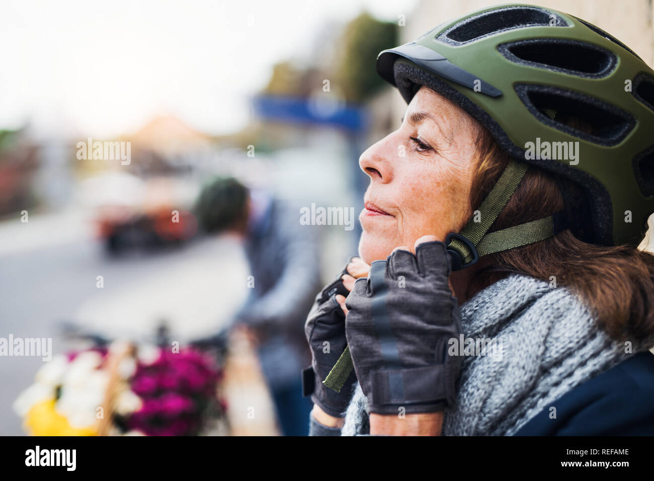 Active senior woman standing all'aperto in città, mettendo su un casco protettivo. Copia dello spazio. Foto Stock