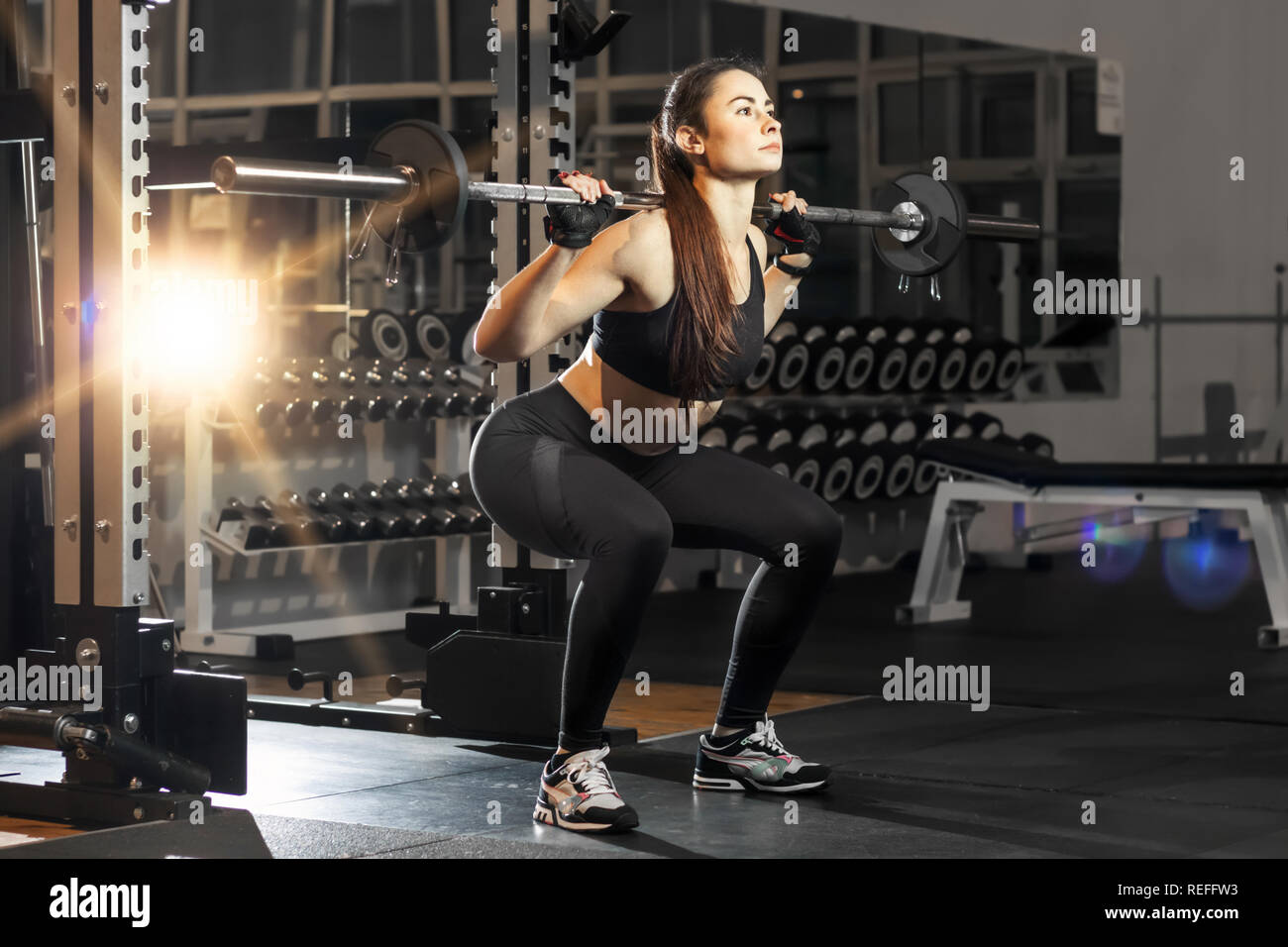 Potente donna attraente squatting con un barbell Foto Stock